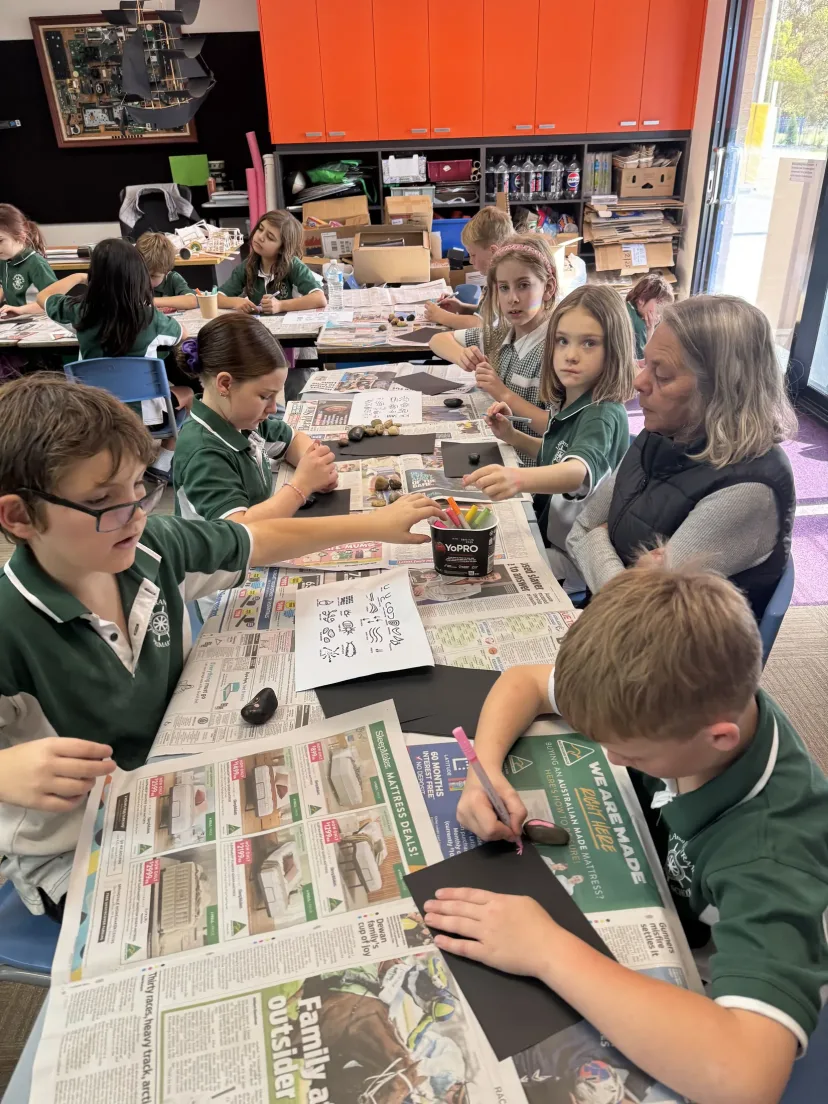 Students spreading newspaper over the tables before an art lesson