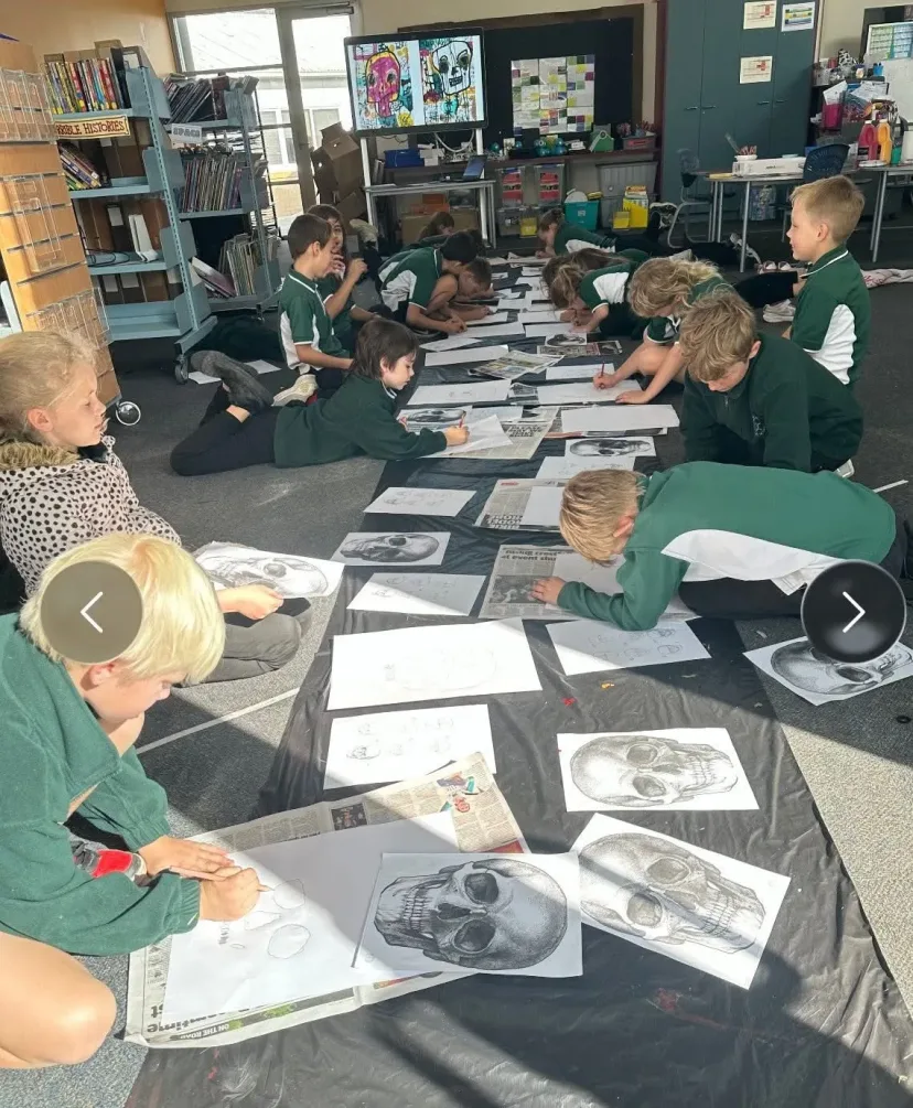 Students lying on the floor working on pencil drawings