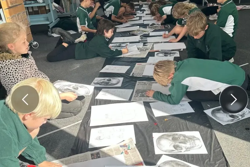 Students lying on the floor working on pencil drawings