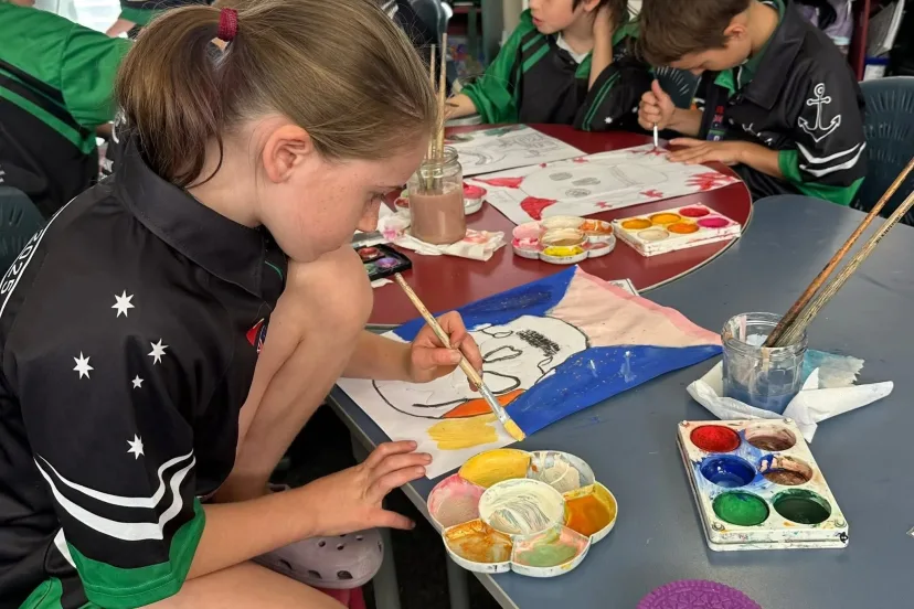 A student painting with watercolours at a classroom table
