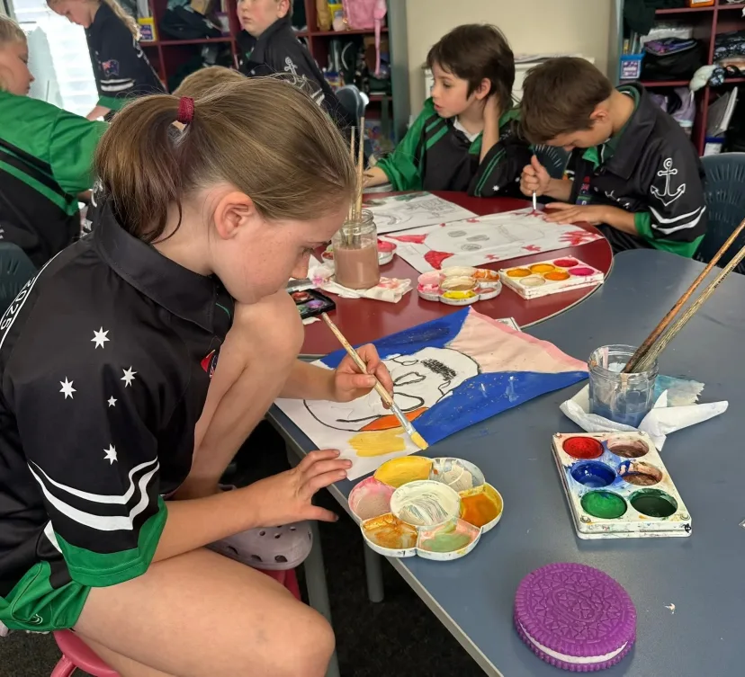 A student painting with watercolours at a classroom table