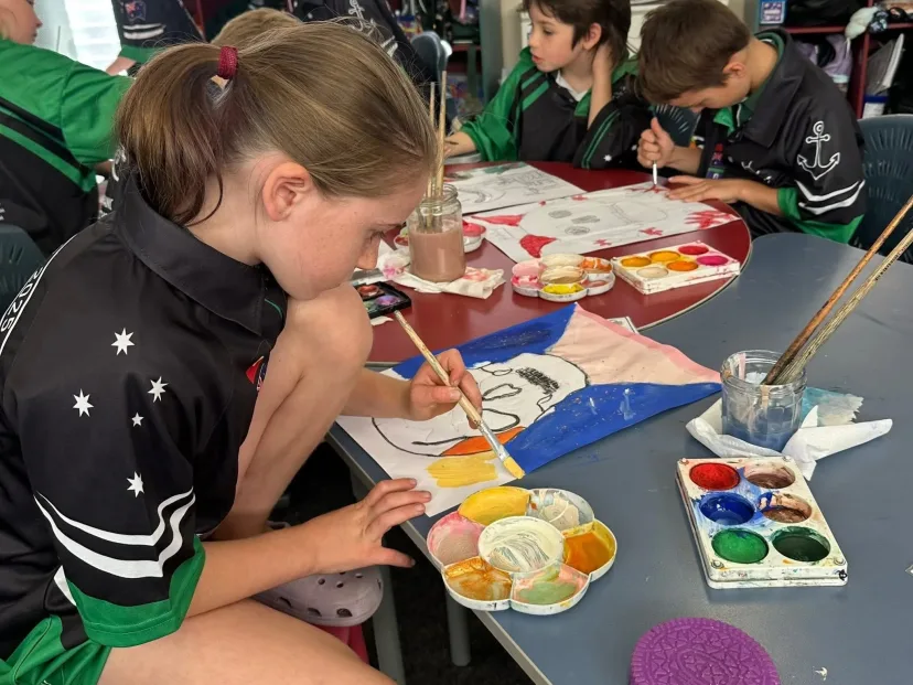 A student painting with watercolours at a classroom table
