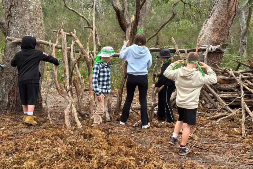 Students building a shelter from fallen branches in the bush