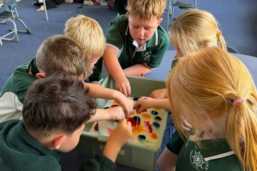 Students crowding round a tray for a science activity