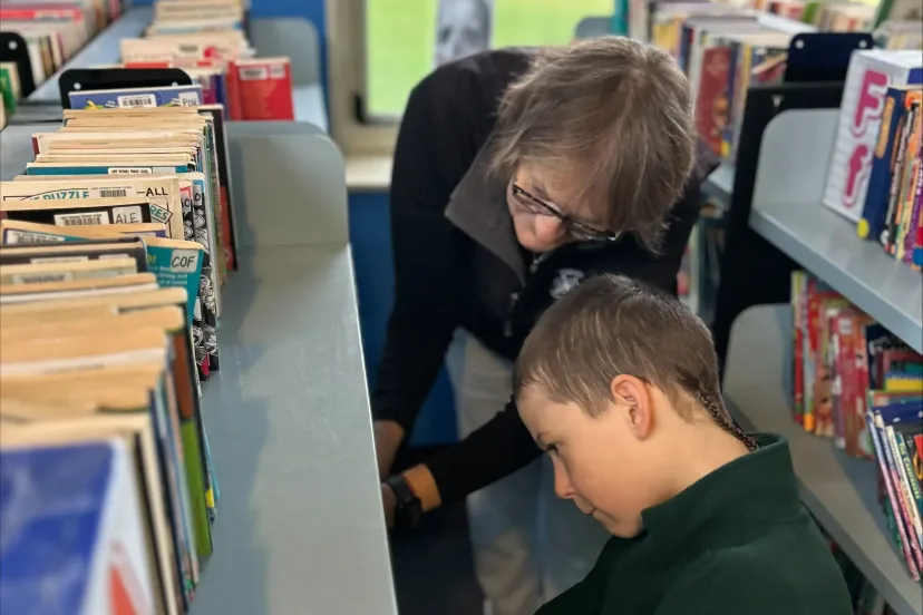 A student choosing a book with help in the school library