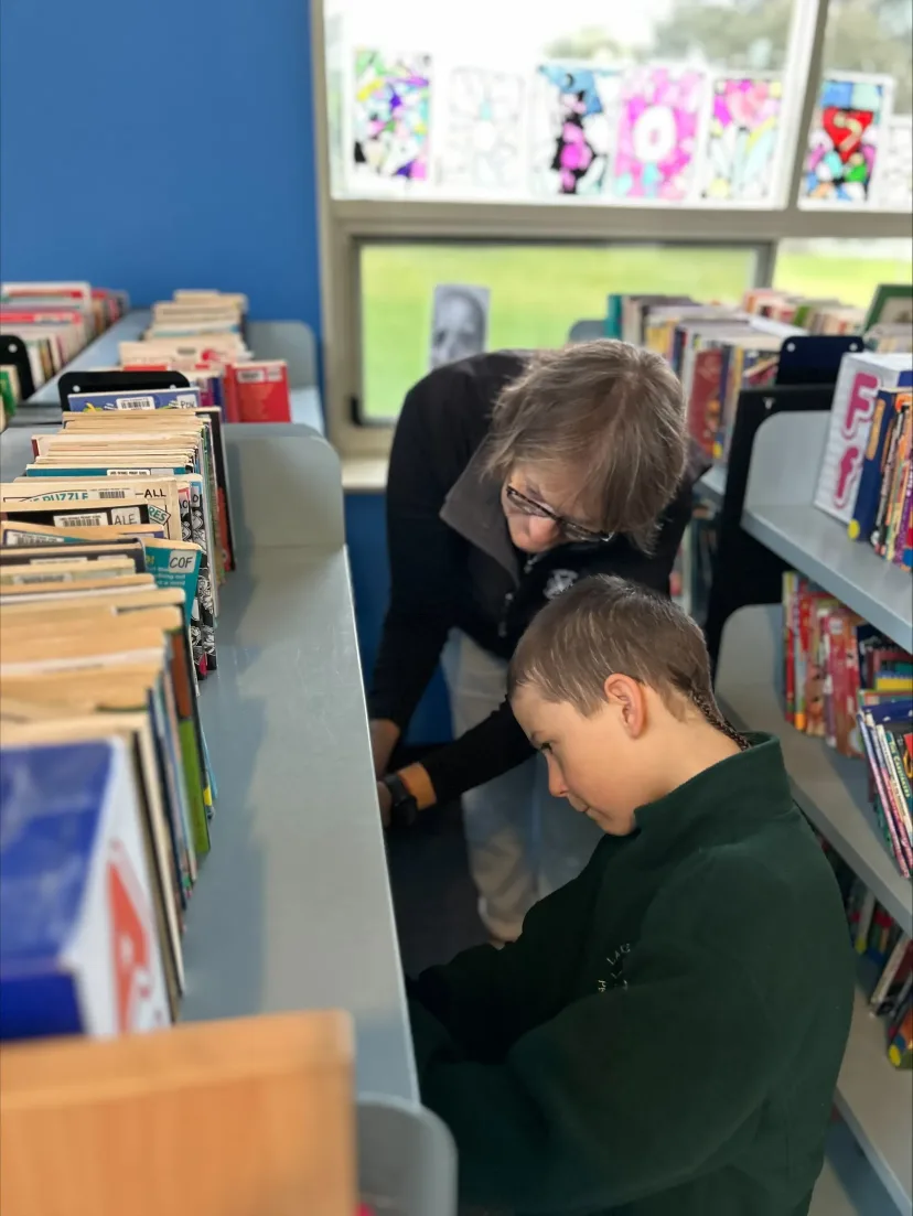 A student choosing a book with help in the school library