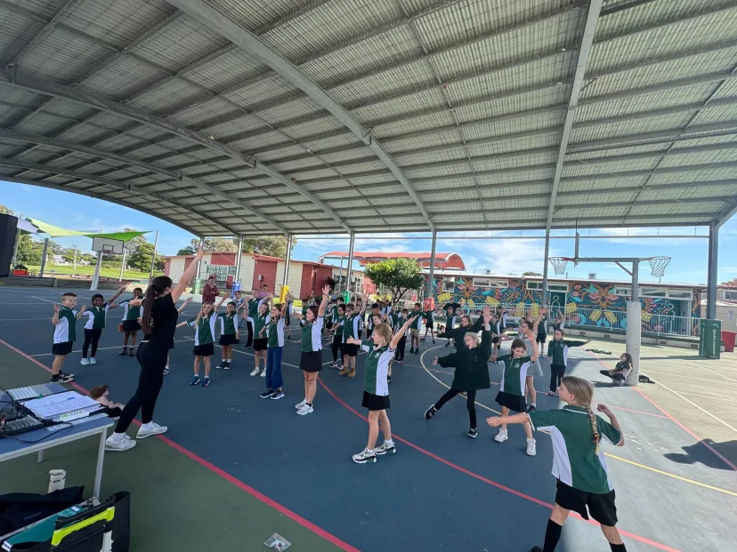 A whole class stretching during PE on the covered court