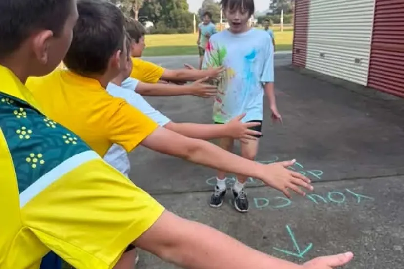 Students in house colours reaching out during a sports day activity
