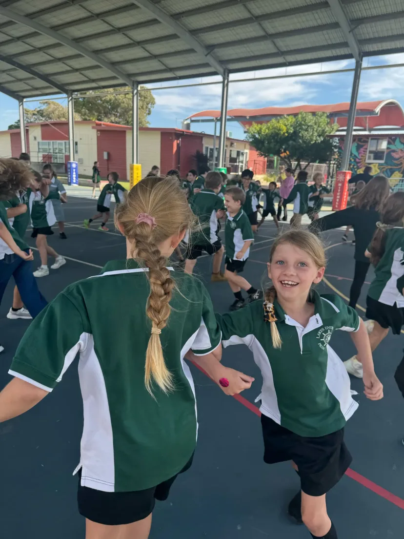 Two students running and laughing on the school court at recess