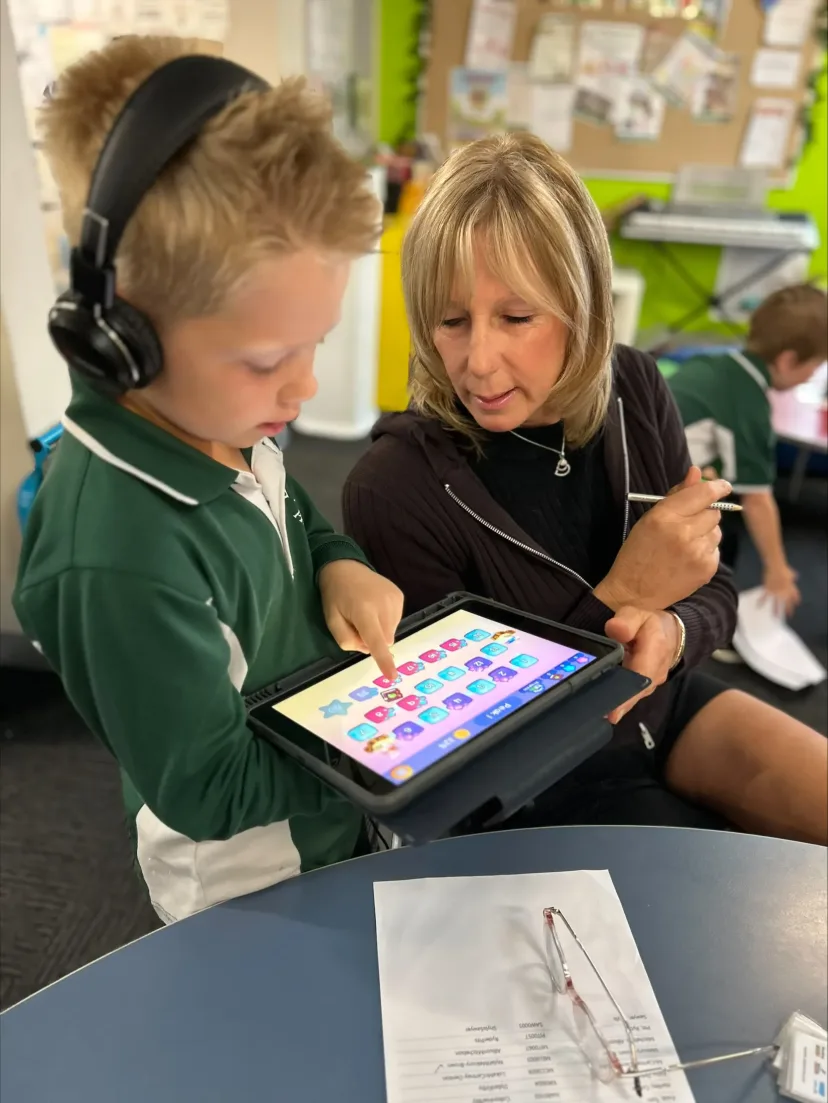 A teacher helping a student with an activity on an iPad